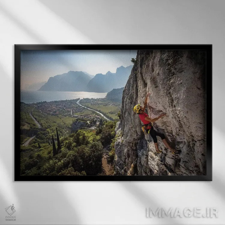 تابلو یک کوهنورد بالای شهر آرکو و دریاچه گاردا، ایتالیا اثر الکس بیوس - نمای قابدار مشکی