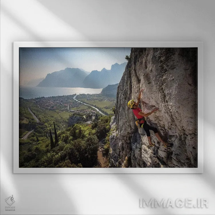 تابلو یک کوهنورد بالای شهر آرکو و دریاچه گاردا، ایتالیا اثر الکس بیوس - نمای قابدار سفید