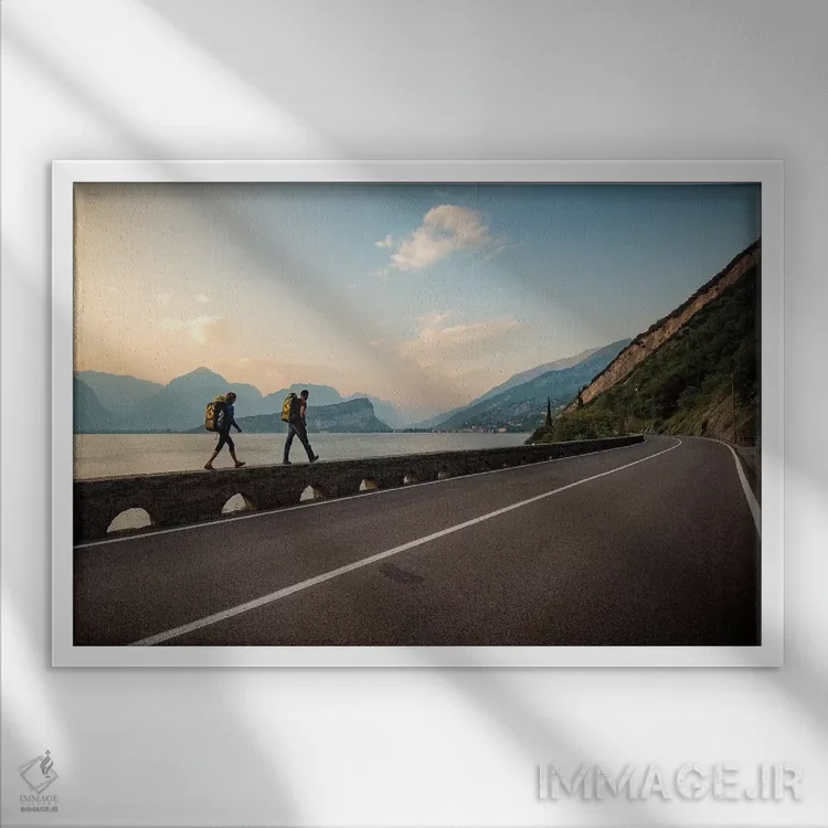 تابلو دو کوهنورد در کنار جاده و دریاچه گاردا، آرکو، ترنتینو، ایتالیا به خانه میروند اثر الکس بیوس - نمای قابدار سفید