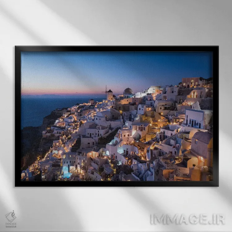 تابلو یونان، سانتورینی. روستای اویا در نور پس از غروب میدرخشد و چراغهای شهر به این منظره نماباور جادویی میبخشند اثر برندا ثارپ - نمای قابدار مشکی