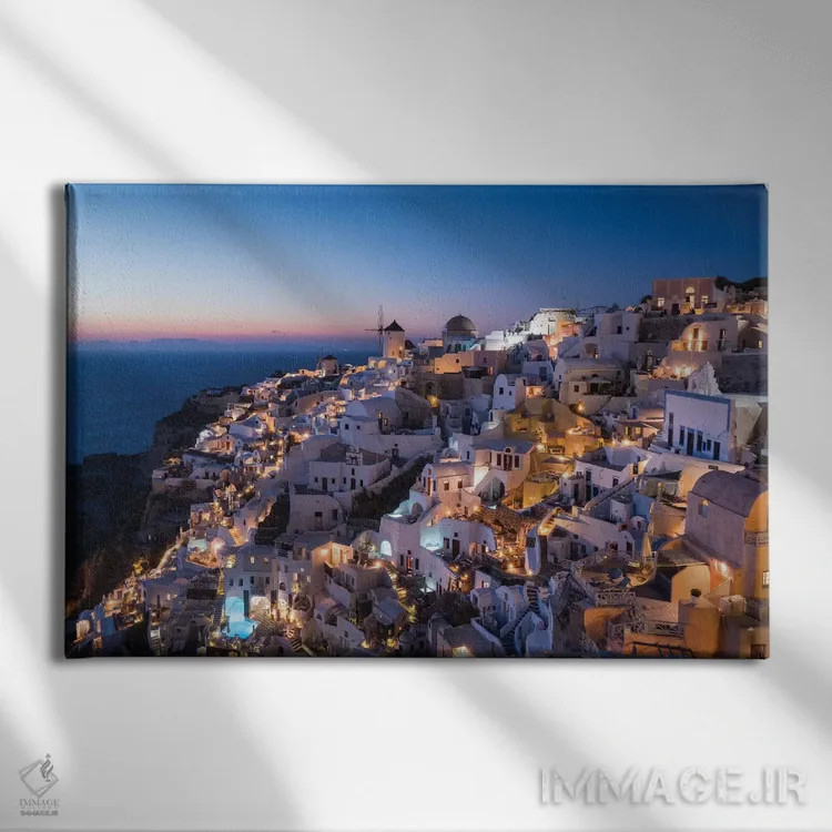 تابلو یونان، سانتورینی. روستای اویا در نور پس از غروب میدرخشد و چراغهای شهر به این منظره نماباور جادویی میبخشند اثر برندا ثارپ - نمای روبهرو روی دیوار
