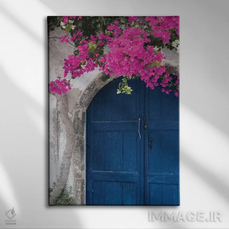 تابلو یونان، سانتورینی. در آبی رنگ و فرسودهای که با شکوفههای صورتی روشن گل کاغذی قاب گرفته شده است اثر برندا ثارپ - نمای روبهرو روی دیوار