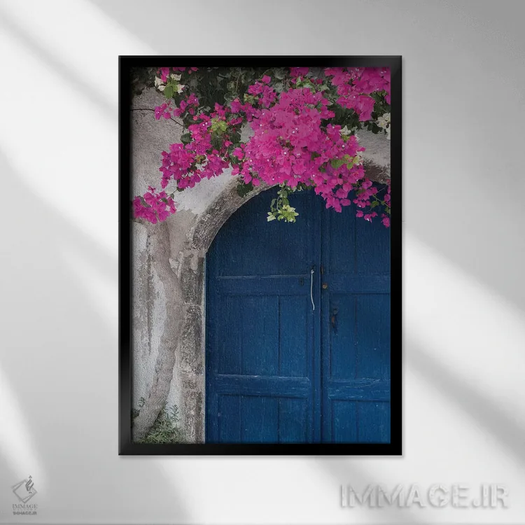 تابلو یونان، سانتورینی. در آبی رنگ و فرسودهای که با شکوفههای صورتی روشن گل کاغذی قاب گرفته شده است اثر برندا ثارپ - نمای قابدار مشکی