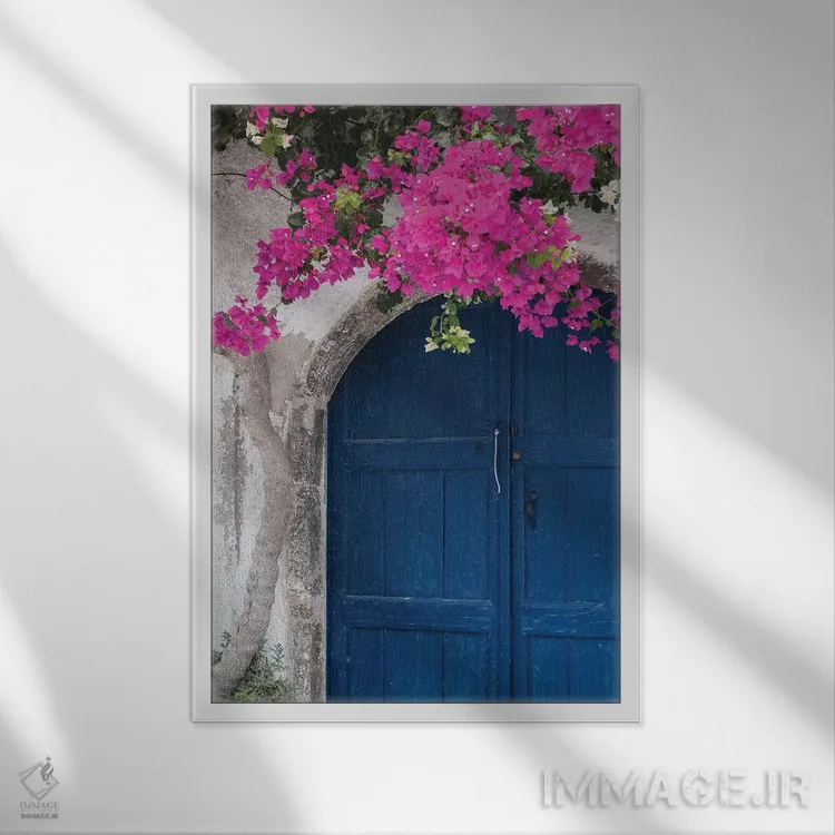 تابلو یونان، سانتورینی. در آبی رنگ و فرسودهای که با شکوفههای صورتی روشن گل کاغذی قاب گرفته شده است اثر برندا ثارپ - نمای قابدار سفید