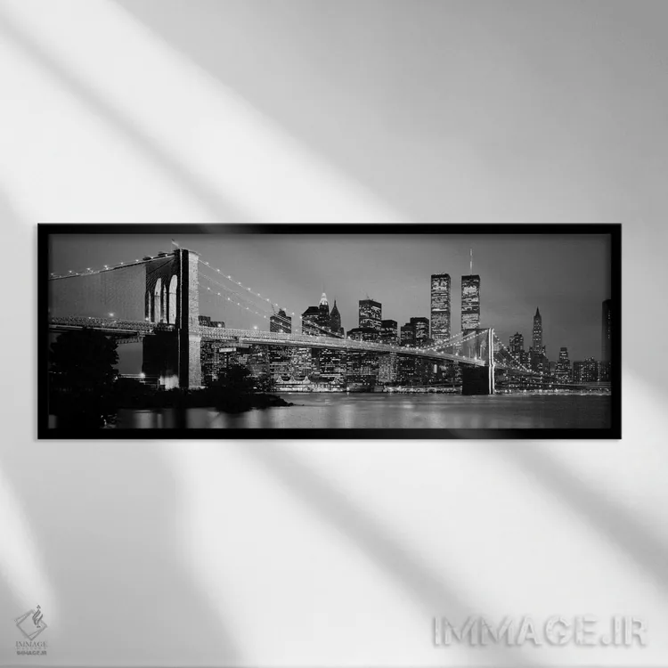 تابلو "پل بروکلین روشن شده با نمای افق منطقه مالی منهتن در پسزمینه به صورت سیاه و سفید، نیویورک سیتی، ایالات نیویورک" اثر پانورامیک ایمجز (استودیو عکاسی عریض) - نمای قابدار مشکی