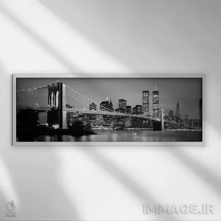 تابلو "پل بروکلین روشن شده با نمای افق منطقه مالی منهتن در پسزمینه به صورت سیاه و سفید، نیویورک سیتی، ایالات نیویورک" اثر پانورامیک ایمجز (استودیو عکاسی عریض) - نمای قابدار سفید