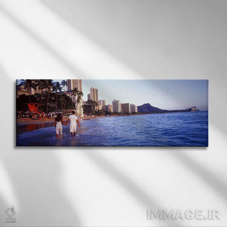 تابلو Waikiki Beach, Honolulu, Oahu, Hawaii, USA,نمای پشت یک زوج در آب راه میروند، ساحل وایکیکی، هونولولو، اوآهو، هاوایی، آمریکا اثر پانورامیک ایمجز (استودیو عکاسی عریض) - نمای روبهرو روی دیوار