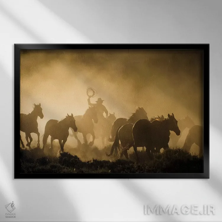 تابلو دکوراتیو سوارکاری که اسب ها را در ابر غبار و نور طلایی طلوع هدایت می ک… اثر شیلا حداد - نمای قابدار مشکی