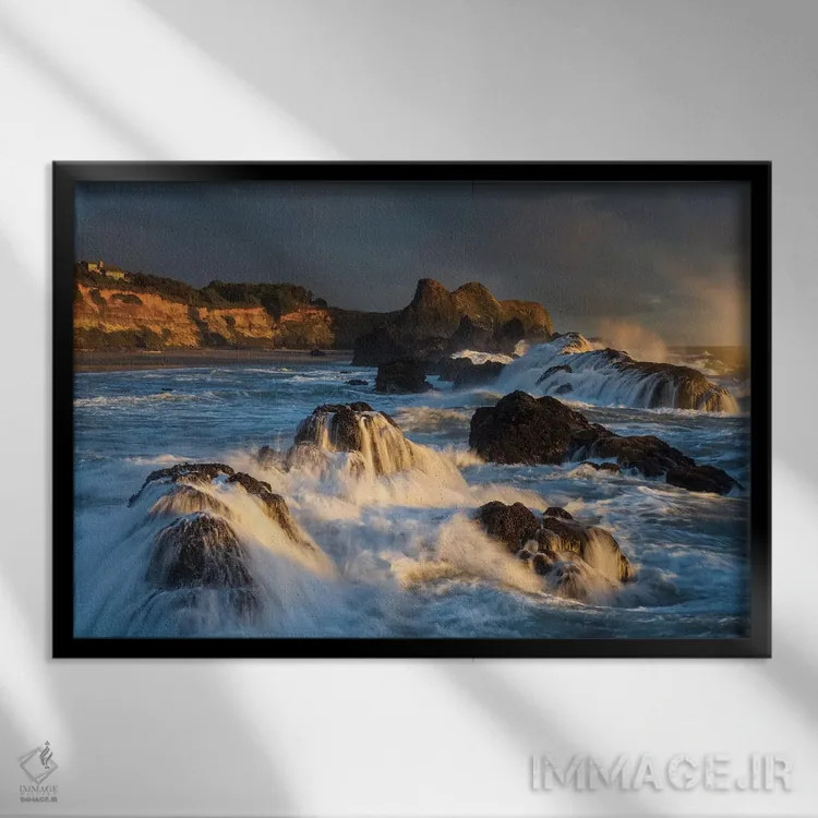 تابلو دکوراتیو امواجی که هنگام غروب به صخره ها برخورد کرده و فرو می ریزند اثر شیلا حداد - نمای قابدار مشکی