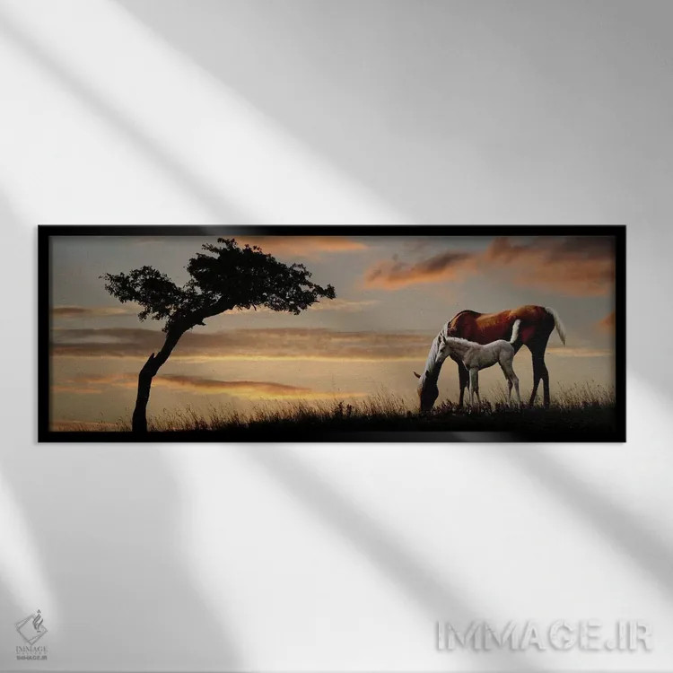 تابلو دکوراتیو مباورها و کره اسب در حال چرا در کنار درخت هنگام غروب اثر پانورامیک ایمجز - نمای قابدار مشکی
