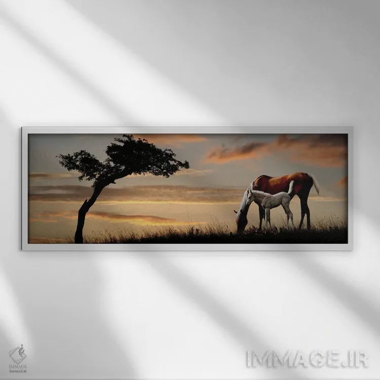 تابلو دکوراتیو مباورها و کره اسب در حال چرا در کنار درخت هنگام غروب اثر پانورامیک ایمجز - نمای قابدار سفید