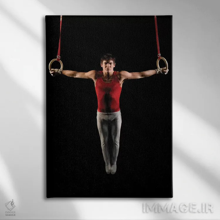 تابلو دکوراتیو مرد جوانی که در حال تمرین روی حلقه های ژیمناستیک است، ج… اثر پانورامیک ایمجز - نمای روبهرو روی دیوار