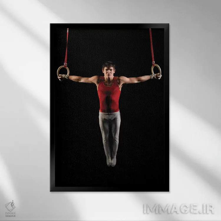 تابلو دکوراتیو مرد جوانی که در حال تمرین روی حلقه های ژیمناستیک است، ج… اثر پانورامیک ایمجز - نمای قابدار مشکی