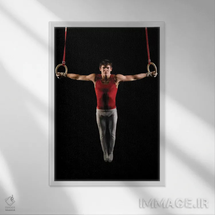 تابلو دکوراتیو مرد جوانی که در حال تمرین روی حلقه های ژیمناستیک است، ج… اثر پانورامیک ایمجز - نمای قابدار سفید