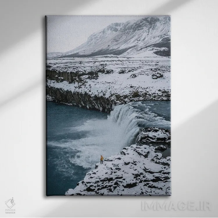 تابلو دکوراتیو فرد کوچکی ایستاده در مقابل آبشار ایسلندی اثر مایکل شاور - نمای روبهرو روی دیوار