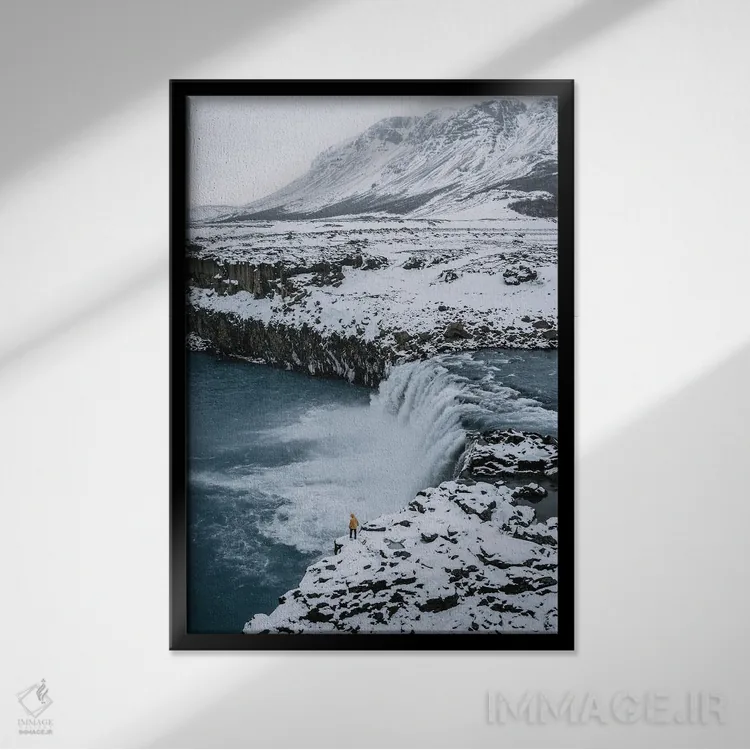 تابلو دکوراتیو فرد کوچکی ایستاده در مقابل آبشار ایسلندی اثر مایکل شاور - نمای قابدار مشکی