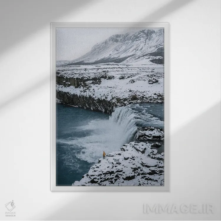تابلو دکوراتیو فرد کوچکی ایستاده در مقابل آبشار ایسلندی اثر مایکل شاور - نمای قابدار سفید