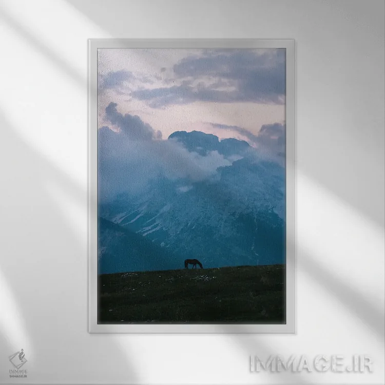 تابلو دکوراتیو اسب تنها در حال چرا در مقابل رشته کوه هنگام ساعت آبی اثر مایکل شاور - نمای قابدار سفید