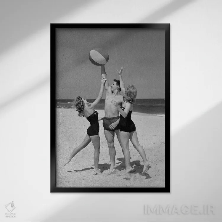 تابلو دکوراتیو نوجوانان در حال پریدن برای گرفتن توپ ساحلی با مایو دهه ۱۹۵… اثر تصاویر وینتج - نمای قابدار مشکی