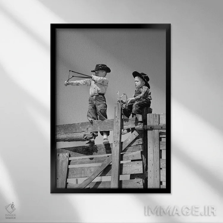 تابلو دکوراتیو دو پسر نوجوان با لباس گاوچران مشغول تیراندازی با فلاخن روی… اثر تصاویر وینتج - نمای قابدار مشکی