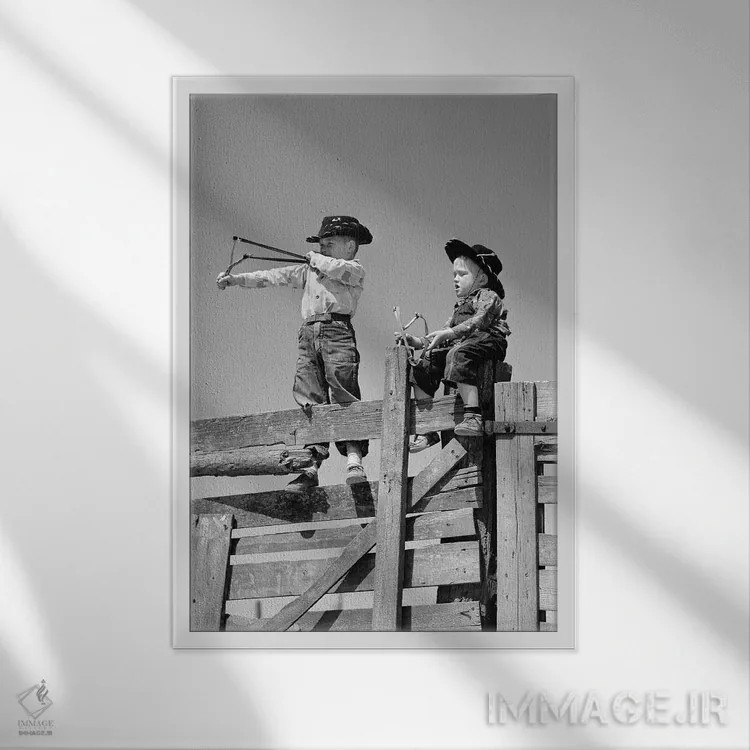 تابلو دکوراتیو دو پسر نوجوان با لباس گاوچران مشغول تیراندازی با فلاخن روی… اثر تصاویر وینتج - نمای قابدار سفید