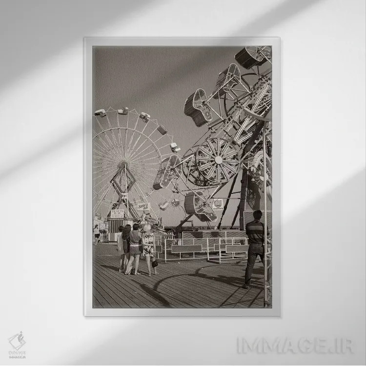 تابلو دکوراتیو گروهی از نوجوانان در حال تماشای وسایل شهربازی روی اسکله ده… اثر تصاویر وینتج - نمای قابدار سفید