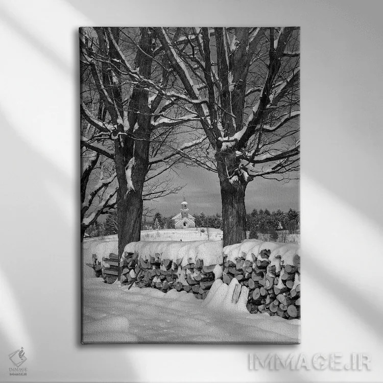 تابلو دکوراتیو توده هیزم پوشیده از برف بین دو درخت با کلیسای روستایی در پ… اثر تصاویر وینتج - نمای روبهرو روی دیوار